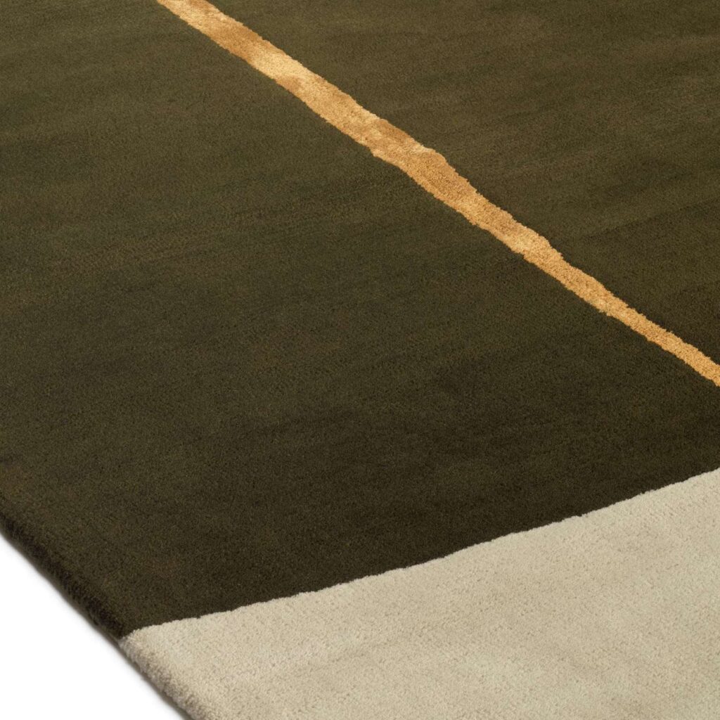 Detail van het Elitis Celeste TA 133 68 02 vloerkleed met een donkergroene basis, een beige rand en een diagonale okergele lijn.