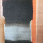 Abstracte Elitis Ceres wandbekleding in grijstinten met oranje accenten en een aardewerk lamp op de voorgrond.