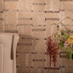 Beige Elitis Ceres Cybele VP 1009-02 behang met geweven structuur en subtiele franjes, gecombineerd met een vaas en bloemen.