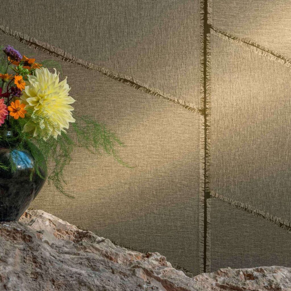 Detailopname van de Elitis Ceres Hera VP 1010 wandbekleding met zichtbare textuur, naast een vaas met kleurrijke bloemen op een rotsachtig oppervlak.