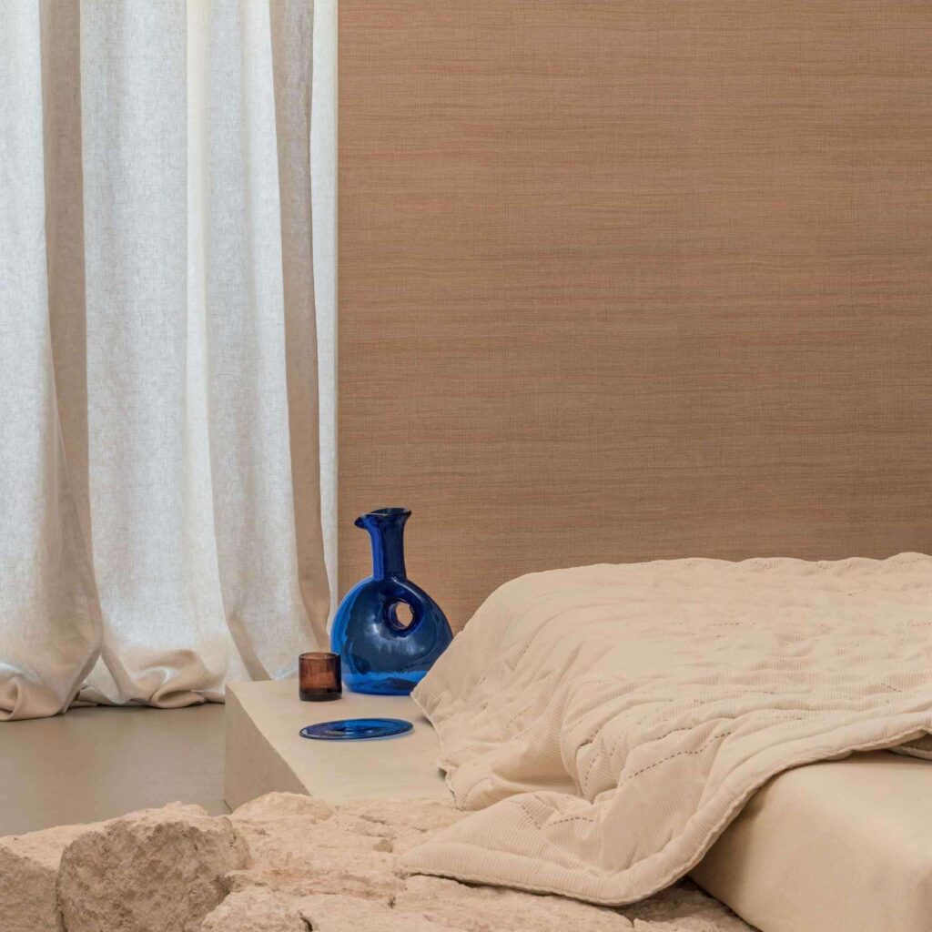 Sfeervolle slaapkamer met Elitis Ceres Rhea VP 1008 wandbekleding, crèmekleurig beddengoed en blauwe decoratieve vaas.