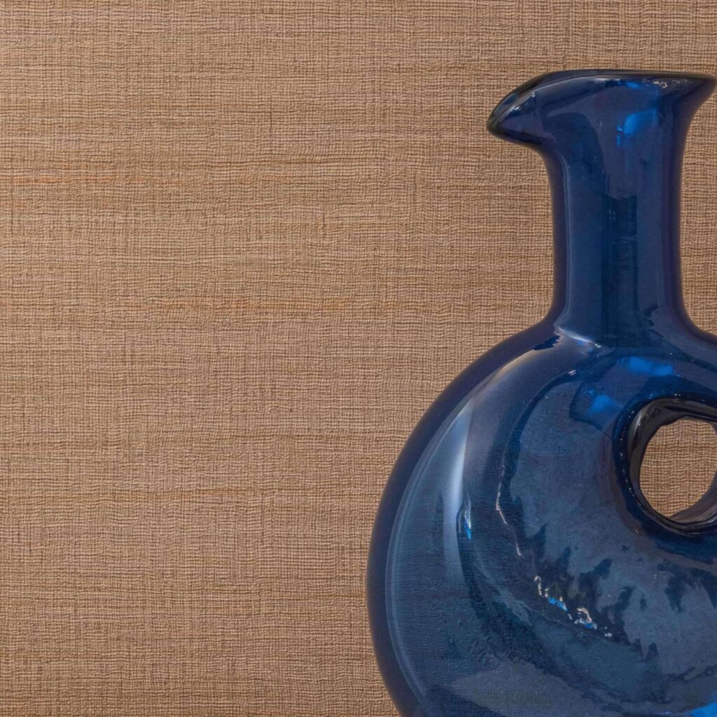 Blauwglazen vaas met ronde uitsparing voor een beige Elitis Ceres Rhea VP 1008 textuurbehang.