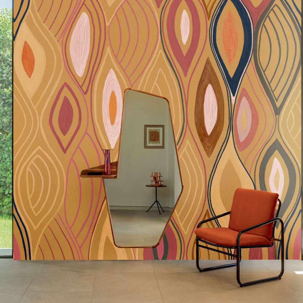Interieur met Elitis Cordes Sensibles x Véronique de Soultrait Arabesque behang in warme tonen, een designstoel en een asymmetrische spiegel.