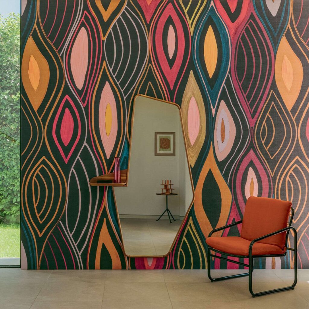 Interieur met Elitis Cordes Sensibles Arabesque VP 1002-02 wandbekleding, een asymmetrische spiegel en een oranje fauteuil.