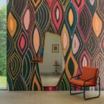 Interieur met Elitis Cordes Sensibles Arabesque VP 1002-02 wandbekleding, een asymmetrische spiegel en een oranje fauteuil.