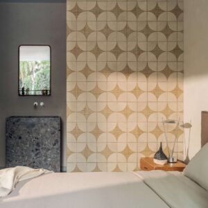 Sfeervol interieur met Elitis Cordes Sensibles behang in geometrisch patroon achter een bed en nachtkastje.