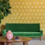 Groene bank voor geometrisch Elitis Cordes Sensibles x Véronique de Soultrait behang met gele cirkelpatronen.