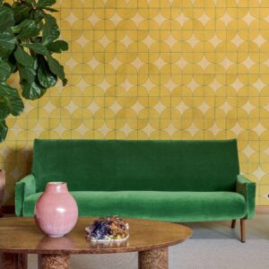 Groene bank voor geometrisch Elitis Cordes Sensibles x Véronique de Soultrait behang met gele cirkelpatronen.