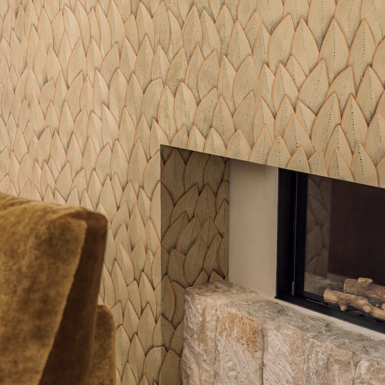 Detail van een modern interieur met Elitis Cordes Sensibles behang van Véronique de Soultrait in het patroon Jonchée, rondom een haard met natuurstenen onderkant.