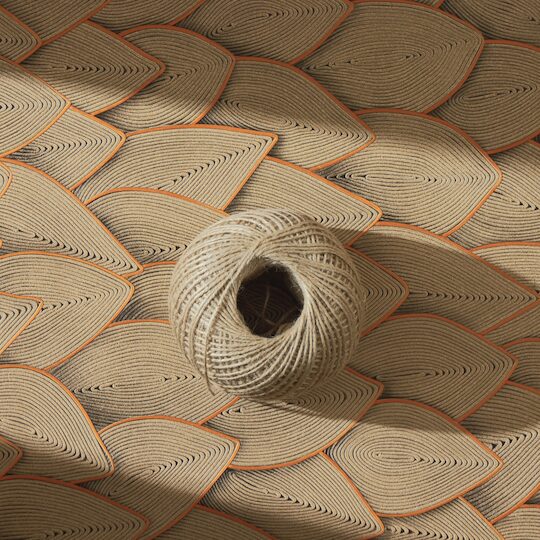 Bol touw op een decoratief Elitis Cordes Sensibles wandpaneel met bladpatroon van gevlochten koord en oranje accenten.