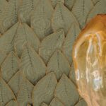 Detail van het textielontwerp 'Jonchée VP 993 60' uit de Elitis Cordes Sensibles collectie van Véronique de Soultrait, met een bladachtig reliëfpatroon en een transparant amberkleurig object op de voorgrond.