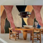 Moderne eetkamer met een houten tafel en stoelen, een grote zwarte hanglamp en een kleurrijk abstract wandpaneel uit de Elitis Cordes Sensibles collectie.
