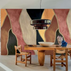 Moderne eetkamer met een houten tafel en stoelen, een grote zwarte hanglamp en een kleurrijk abstract wandpaneel uit de Elitis Cordes Sensibles collectie.