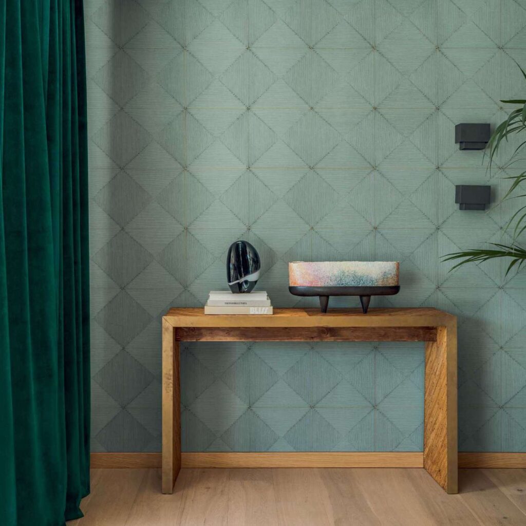 Houten console tegen een geometrisch patroonbehang uit de Elitis Cordes Sensibles collectie met decoratieve objecten en kunstboek.