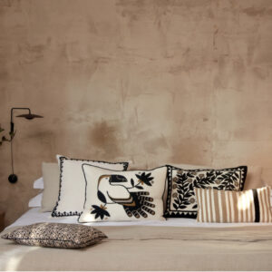 Sfeervolle slaapkamer met Elitis Cristobal kussen CO 249 88 02 en andere decoratieve kussens op een opgemaakt bed.
