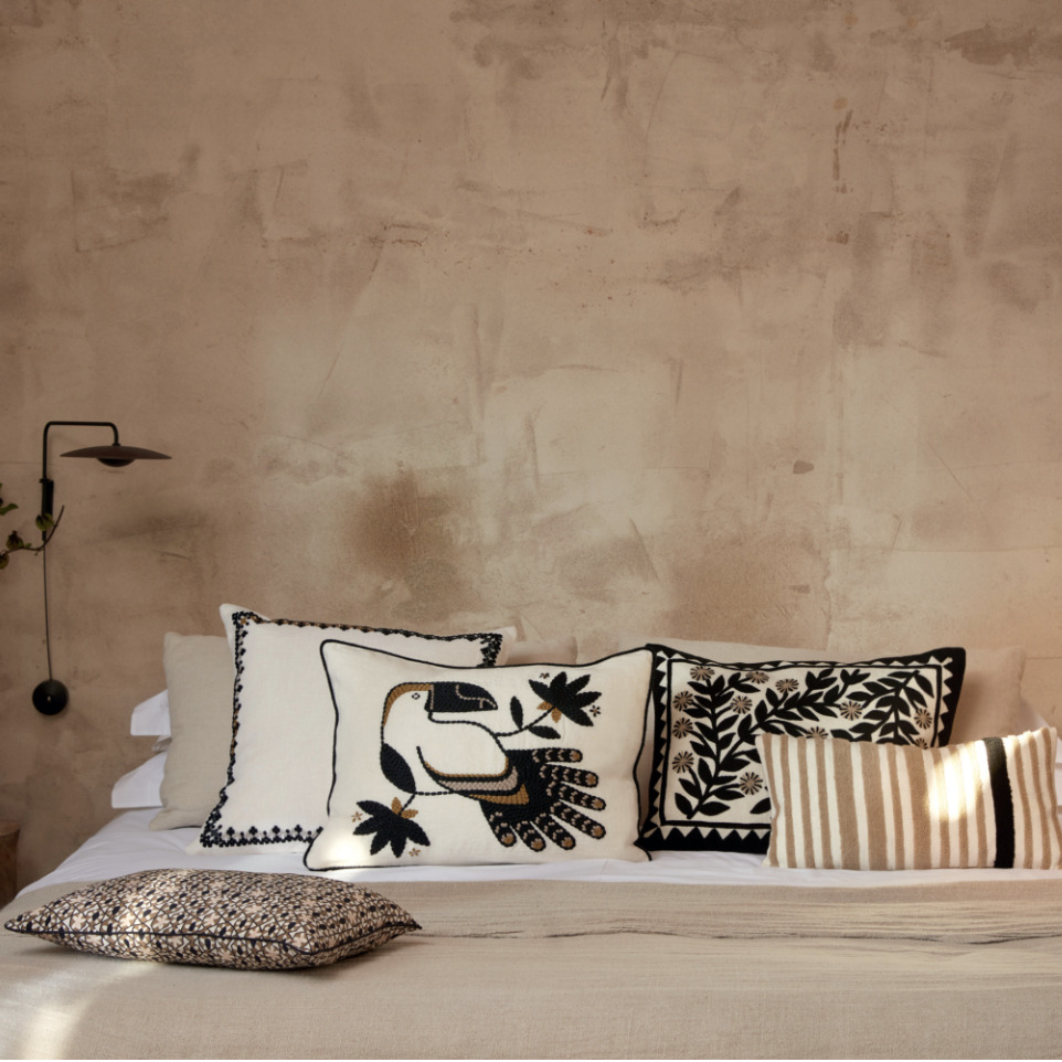 Sfeervolle slaapkamer met Elitis Cristobal kussen CO 249 88 02 en andere decoratieve kussens op een opgemaakt bed.
