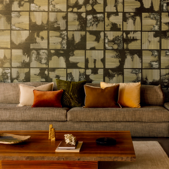 Moderne zithoek met Elitis Edmond CO 262 kussens op een grijze bank en een kunstzinnige wand met grafisch patroon.