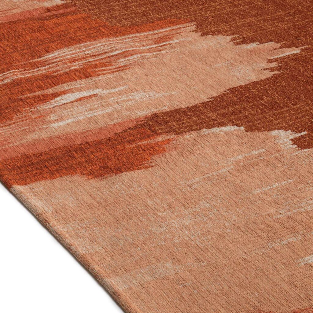 Detail van het Elitis Emile TA 135 34 02 tapijt met een abstract patroon in rood- en aardetinten.
