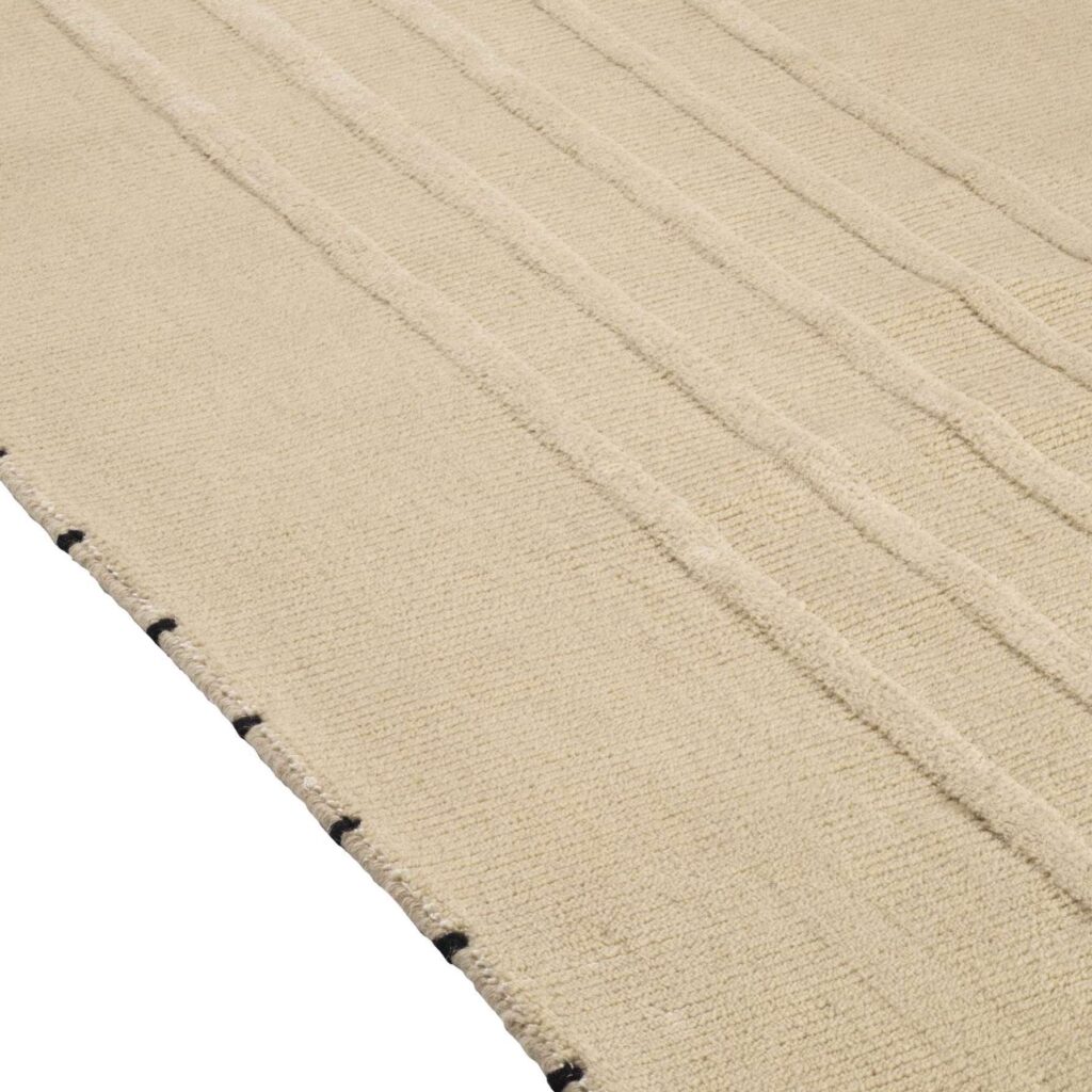Detail van het Elitis Ernest TA 132 04 02 vloerkleed met een geweven structuur en subtiele reliëflijnen in beige tint.
