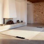 Licht en minimalistisch interieur met het Elitis Ernest TA 132 04 02 vloerkleed voor een moderne open haard.