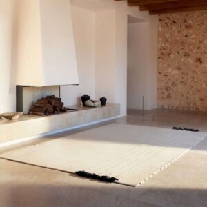 Licht en minimalistisch interieur met het Elitis Ernest TA 132 04 02 vloerkleed voor een moderne open haard.