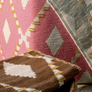 Detailopname van Elitis Escondido PALOHA LR 362 56 textiel met kleurrijk Azteeks geïnspireerd patroon in roze, bruin en grijstinten.