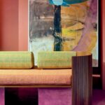 Designbank bekleed met Elitis Excentric Andy stof in een kleurrijke interieursetting met abstract schilderij op de achtergrond.