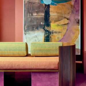 Designbank bekleed met Elitis Excentric Andy stof in een kleurrijke interieursetting met abstract schilderij op de achtergrond.