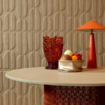 Rond tafelblad met decoratieve objecten voor een beige Elitis Forms Twisted Suedine behang met 3D-patroon.