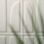 Detailopname van de Elitis Forms Wall Twisted Lin RM 1053-01 wandbekleding met een reliëfstructuur en een plant op de voorgrond.