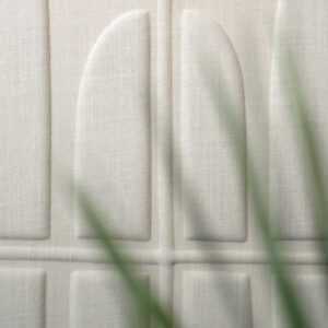 Detailopname van de Elitis Forms Wall Twisted Lin RM 1053-01 wandbekleding met een reliëfstructuur en een plant op de voorgrond.