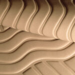 Detail van Elitis Forms Wall Wave Flanelle RM 1055 05 met golvend, textielachtig reliëfpatroon in beige tint.