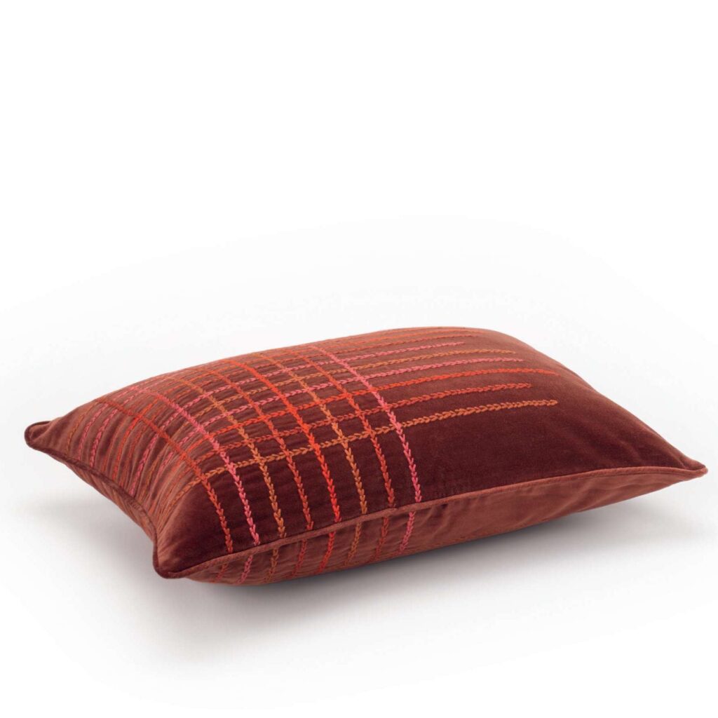 Zijaanzicht van het Elitis Henry Co 255 72 02 kussen met roodbruine stof en kleurrijk geborduurd ruitpatroon.