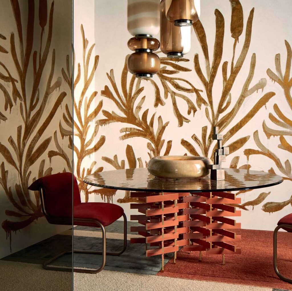 Sfeervolle interieursetting met Elitis Kintsugi Algues Dorées behang, ronde tafel met artistiek onderstel en moderne verlichting.