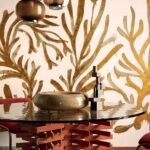 Designinterieur met een ronde tafel, sculpturale decoratie en een wand met goudkleurig Elitis Kintsugi Algues Dorees behang.
