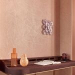 Interieur met Elitis Kintsugi behang in zachte roze tinten, een kunstige wanddecoratie en een stijlvol bureau met decoratieve voorwerpen.