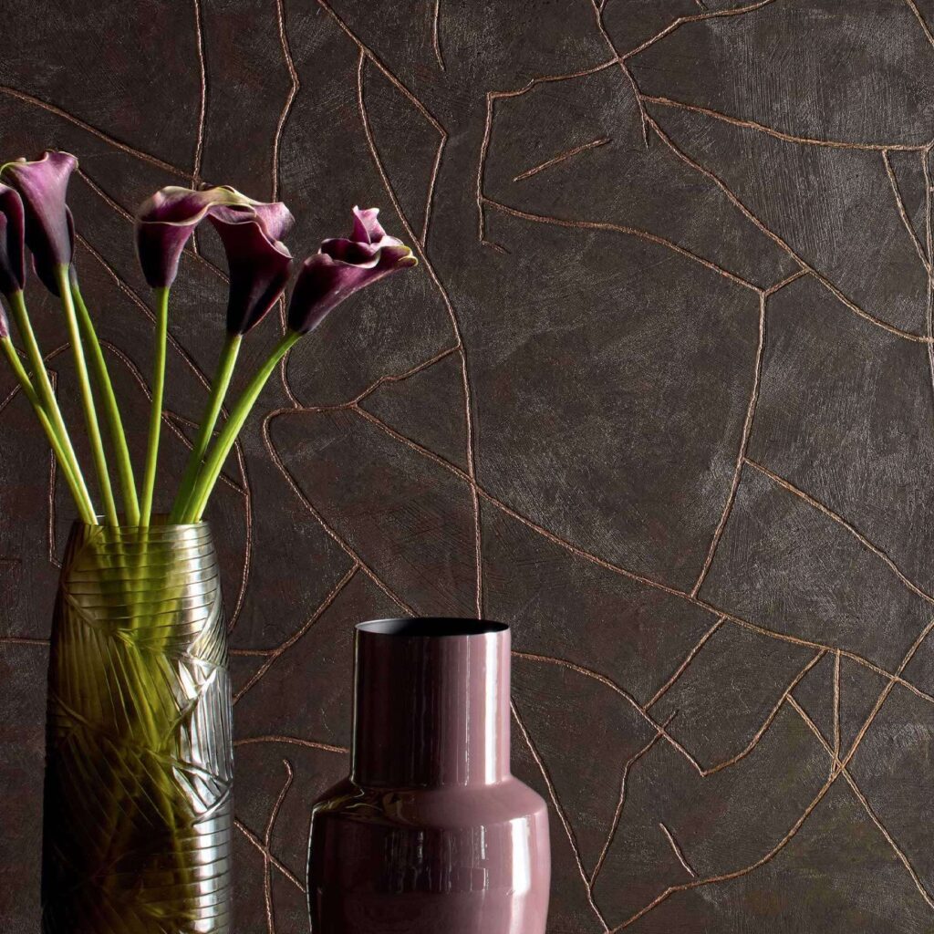 Twee designvazen met bloemen staan voor een donkere Elitis Kintsugi muur met goudkleurige scheurpatronen.