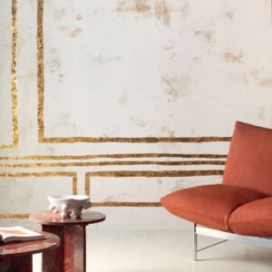 Moderne interieursetting met een Elitis Kintsugi wandbekleding, een roestbruine designstoel en marmeren bijzettafels.