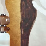 Detail van Elitis Kintsugi-behang met abstracte vormen in goud, bruin en wit naast een moderne vaas met glazen elementen.