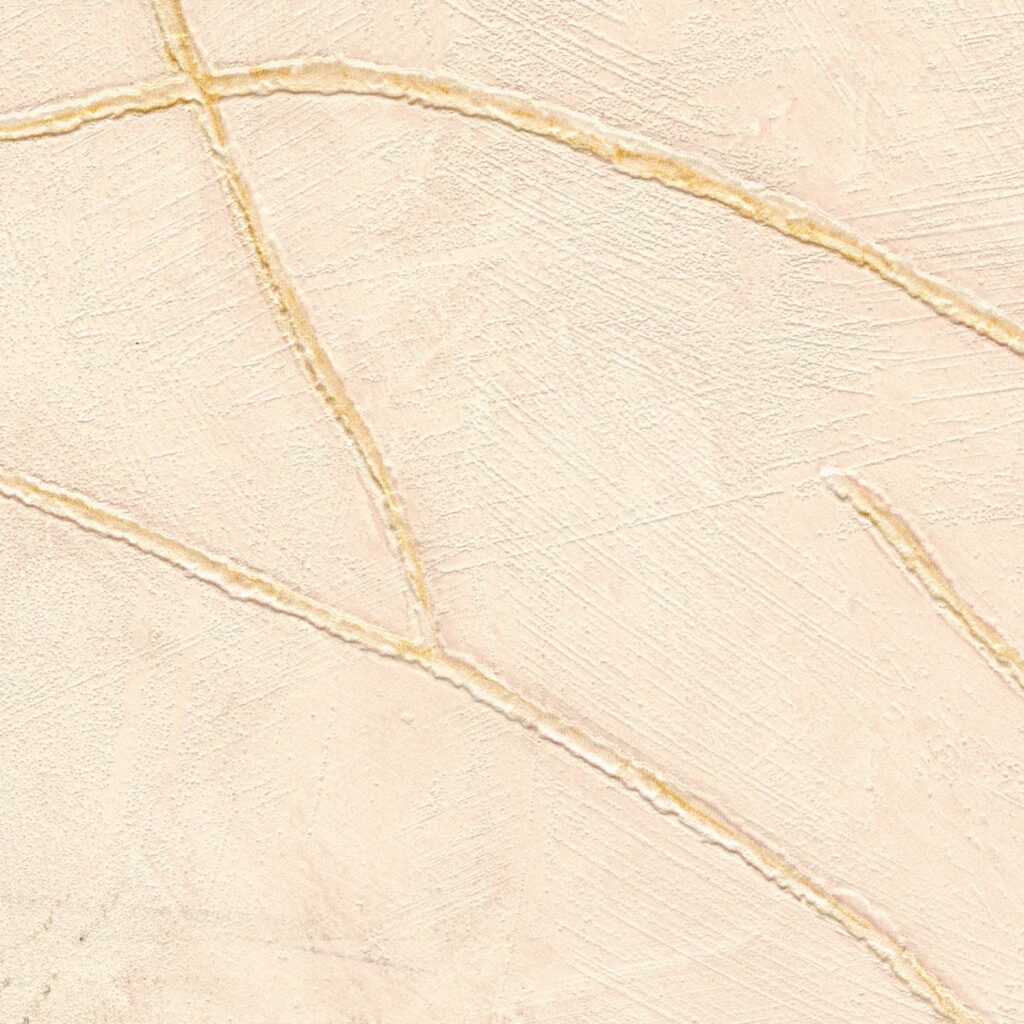 Beige Elitis Kintsugi VP 1004 52 behang met een textuur van subtiele goudkleurige scheurlijnen.