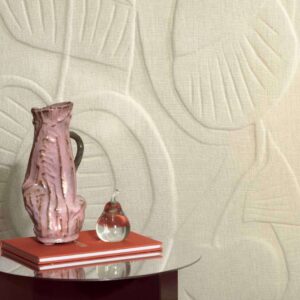 Roze keramische vaas en glazen peerornament op oranje boeken voor een beige reliëfbehang uit de Elitis Le Jardin d’Aloès Colosse Fruitier collectie.