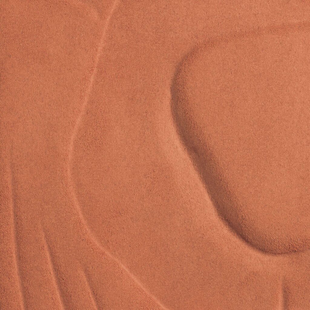 Close-up van een textieloppervlak met reliëf in een warme terracottatint uit de Elitis Le Jardin d’Aloès Colosse Fruitier collectie.