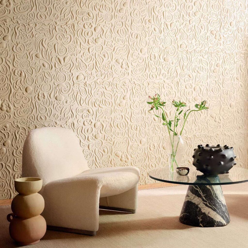 Sfeervolle zithoek met een Elitis ‘Le Jardin d’Aloès’ reliëfbehang, designstoel en glazen salontafel met marmeren voet.