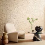 Sfeervolle zithoek met een Elitis ‘Le Jardin d’Aloès’ reliëfbehang, designstoel en glazen salontafel met marmeren voet.