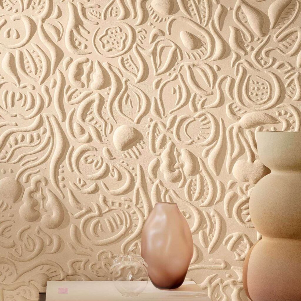 Beige 3D-behang met abstract reliëfpatroon uit de Elitis Le Jardin d’Aloès collectie, met decoratieve vazen op de voorgrond.