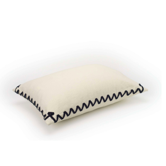 Crèmekleurig Elitis Liberty kussen met decoratief zwart zigzagstiksel langs de randen, zijaanzicht.