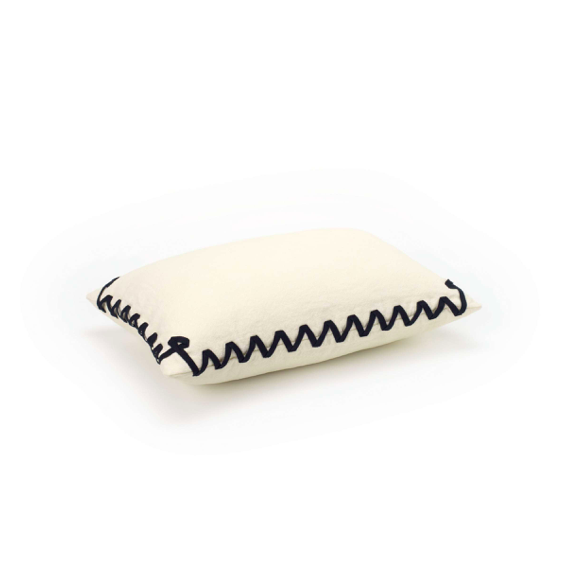 Crèmekleurig Elitis Liberty CO 265 02 02 kussen met decoratieve zwarte zigzagstiksel langs de randen.