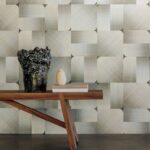 Houten tafel met decoratieve vazen tegen een Elitis Maestria Circe RM 1072 grijze designbehangmuur.