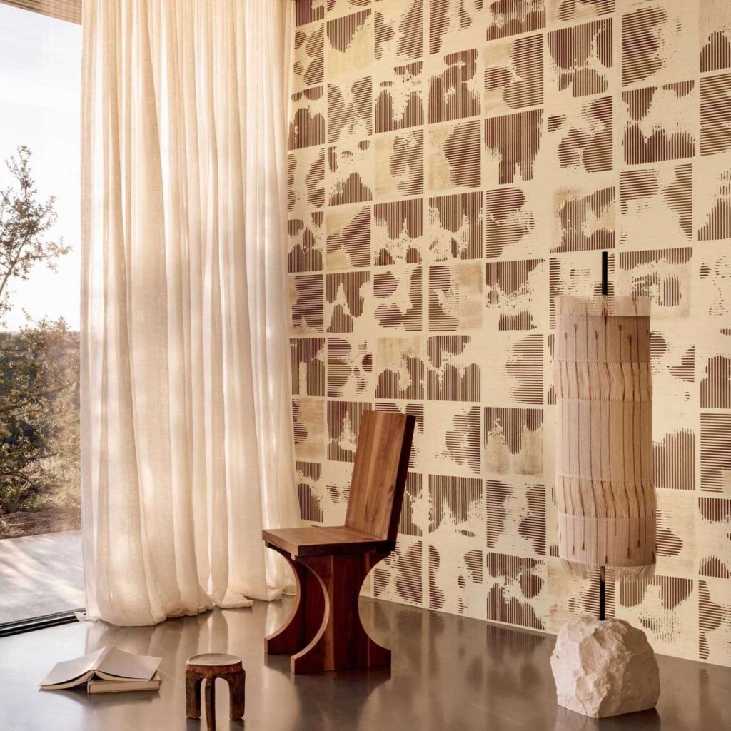 Interieur met Elitis Maestria Kalliste RM 1077 02 behang, houten designstoel, sculpturale lamp en lichtgordijn bij een groot raam.