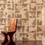 Houten designstoel voor een muur met Elitis Maestria Kalliste RM 1077 02 behang in abstract vierkantenpatroon.